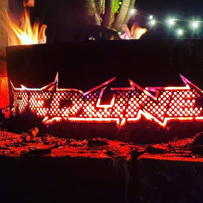 Custom Redline branded steel fire pit glowing at night